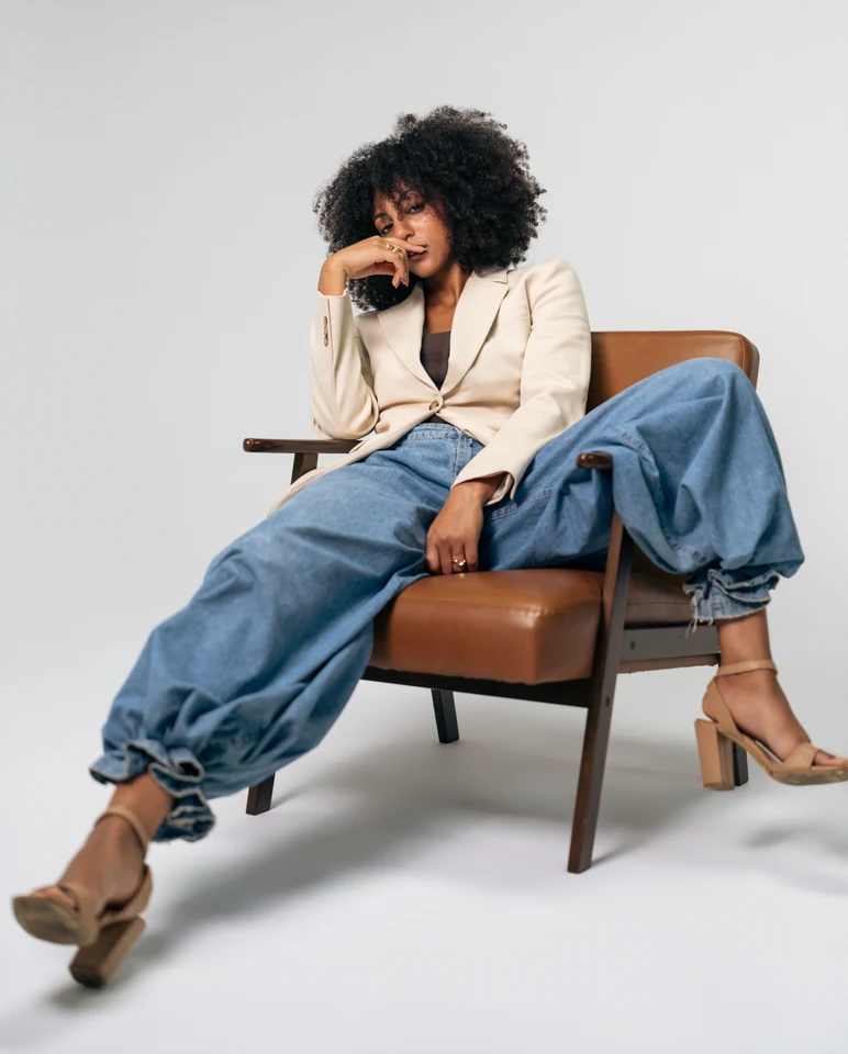 Morgan Miller seated in a cream blazer and wide-leg jeans